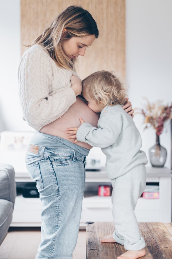 Enfant qui fait un bisou sur le ventre de sa maman, séance grossesse à domicile à La Teste-de-Buch