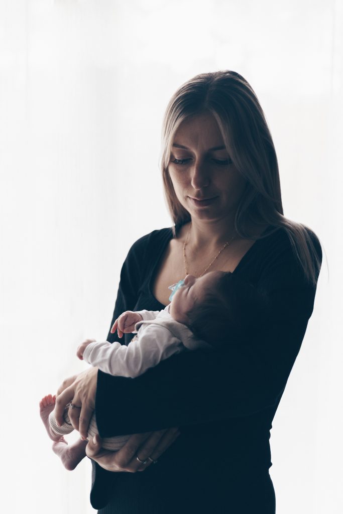 Maman et son bébé à contre-jour près de la fenêtre, séance naissance à domicile à La Teste-de-Buch