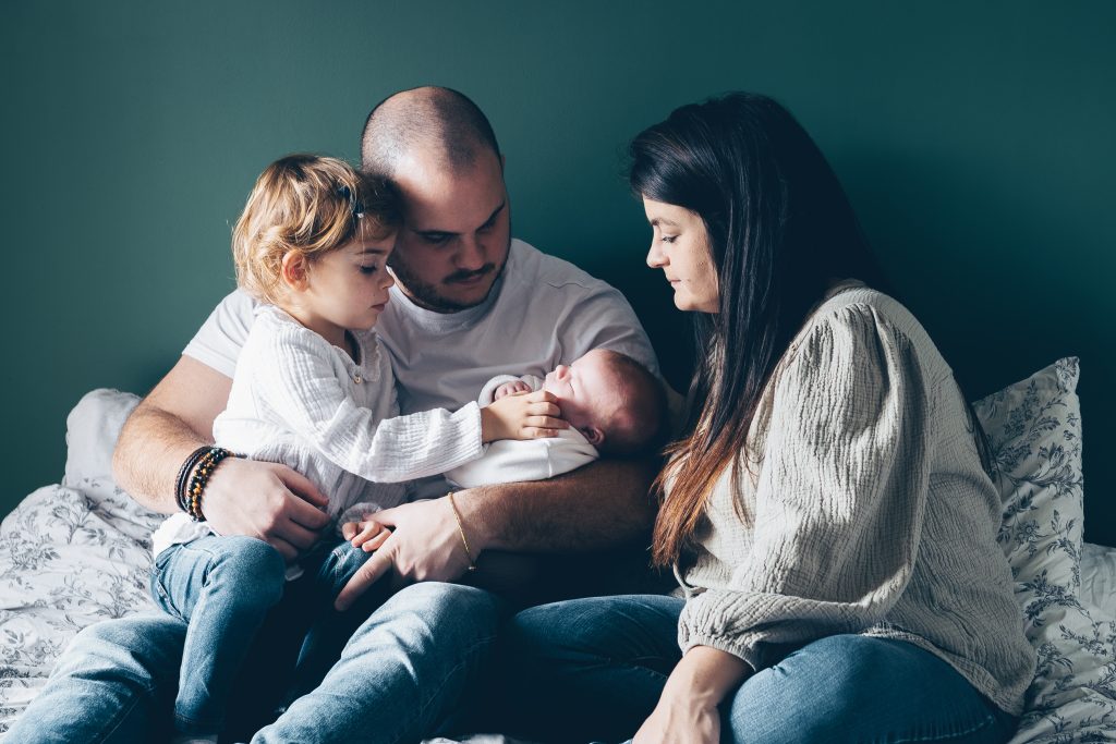 Famille réunie sur le lit avec bébé, séance photo naissance à domicile à Mios
