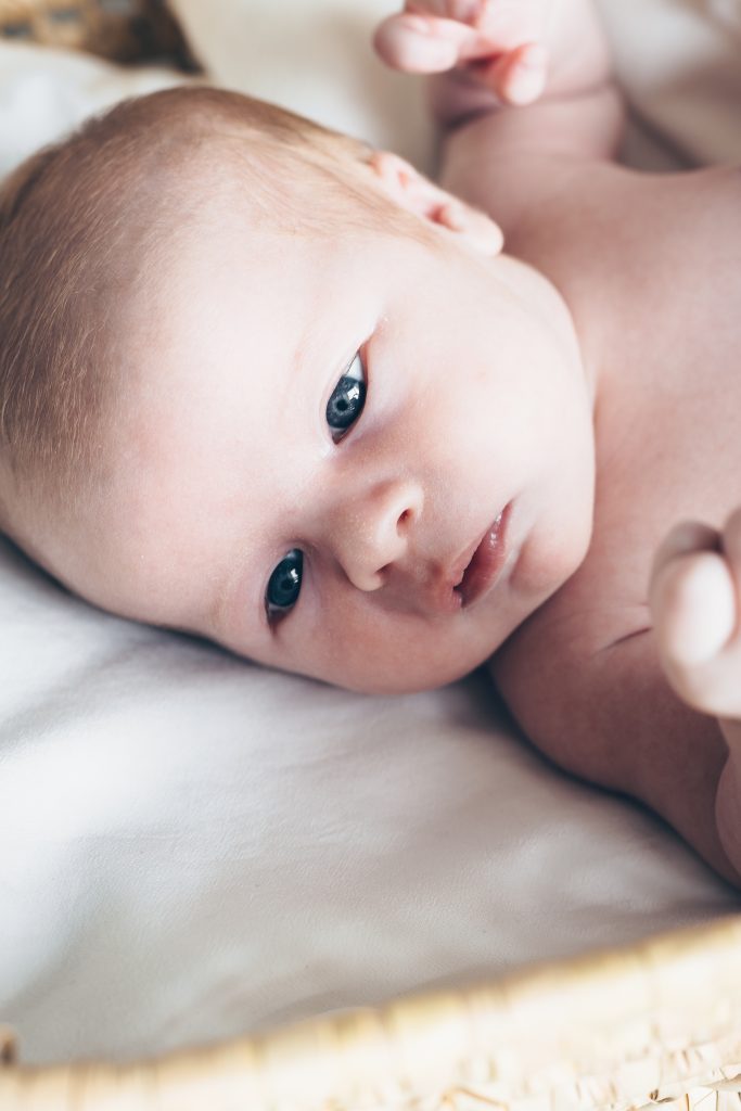 Portrait de nouveau-né endormi dans son couffin, séance naissance au Teich